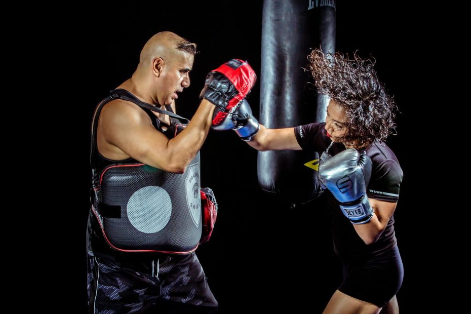 A woman boxing with a trainer in a gym, showcasing strength and focus.