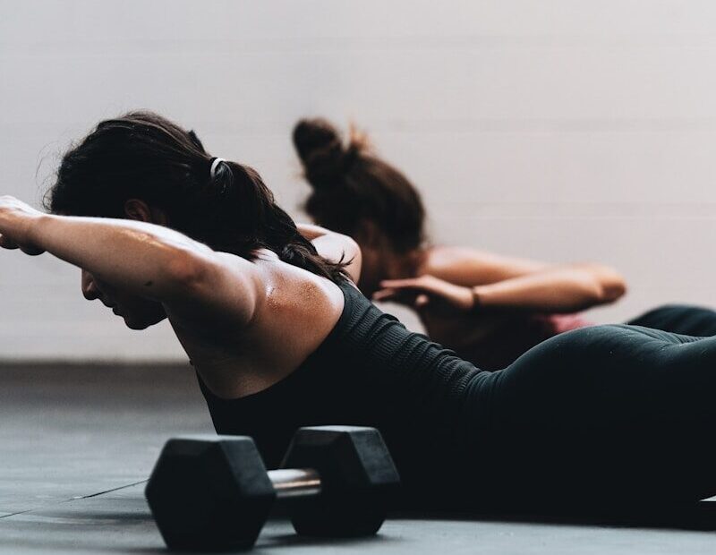woman in black tank top and black leggings lying on black floor